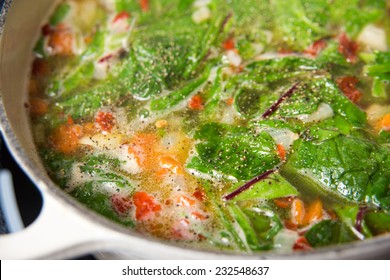 Making Fresh Soup With Baby Greens, Vegetables, And Chicken Bone Broth 