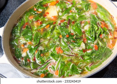 Making Fresh Soup With Baby Greens, Vegetables, And Chicken Bone Broth 