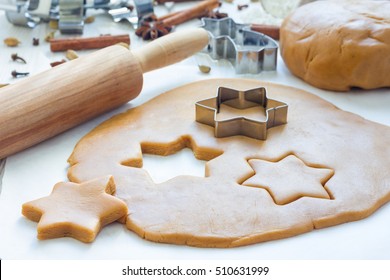 Making gingerbread cookies. Dough, metal cutter and rolling pen on wooden table, spices on background, horizontal
