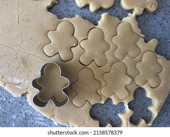 making gingerbread cookies mini gingerbread man biscuits cut out on a floured surface with cookie cutter