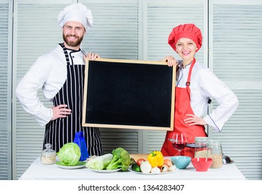 Making Good Food. Chef And Cook Helper Teaching Master Class. Couple Of Man And Woman Holding Empty Blackboard In Cooking School. Master Cook And Prep Cook Giving Cooking Class, Copy Space.