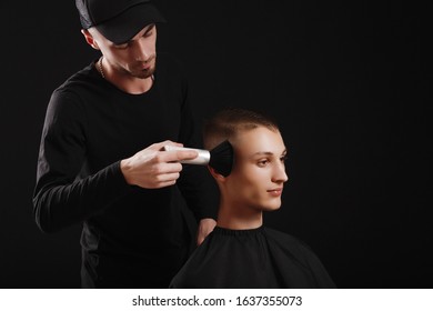 Making Haircut Look Perfect With A Brush. Young Man Getting Haircut By Hairdresser While Sitting In Chair At Barbershop On Black Background.