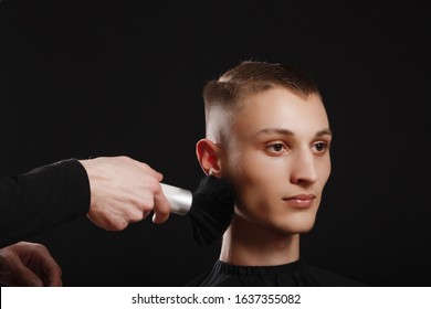 Making Haircut Look Perfect With A Brush. Young Man Getting Haircut By Hairdresser While Sitting In Chair At Barbershop On Black Background.