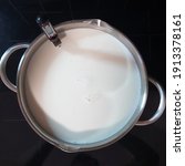 Making halumi cheese and ricotta with your own hands. Step-by-step photos of the process. Preparation and heating of milk in a saucepan with a thermometer. Square stock photo