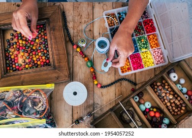 Making Of Handmade Jewellery. Box With Beads On Old Wooden Table. Top View With Woman Hands - Tutorial To Learn How To Make Bracelets And Jewellery Online And Alternative Home Job