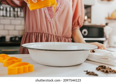 Making holiday baked goods on Christmas Eve at home in kitchen. homemade baking. young woman in smart festive dress pours honey into dough. Making gingerbread dough