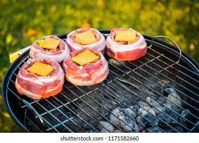 Making Home Made Beer Can Bacon Burgers On Barbecue Grill. Preparing Stuffed Patties, Wrapped  In Bacon And Grilling On Indirect Heat In Nature At Back Yard BBQ Picnic. Low And Slow Technique With Sun