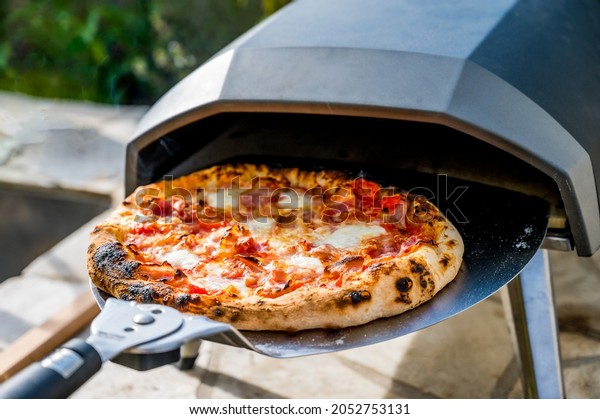 Making\
homemade pizza in portable high temperature gas  oven. Delicious\
pizza is baking in gas oven furnace for home made Neapolitan pizza.\
Special gas fueled pizza oven for picnic or\
party.