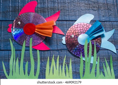 Making homemade toy fish from the CD. Handmade children's project. Step by step photo instructions. Step 8: Two fish made of the CD on a blue wooden background