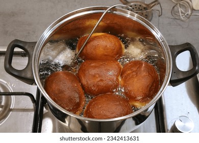 Making homemade yeast raised donuts - deep frying in lard fat with a kitchen thermometer probe. Polish donuts made for Tlusty Czwartek (Fat Thursday) holiday in Poland.