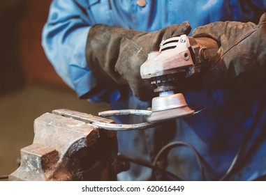 Making of horseshoe. Male worker polishing horseshoe. - Powered by Shutterstock