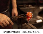 Making iron, metal flower. Bearded man, blacksmith manually forging the molten metal on the anvil in smithy with spark fireworks. Concept of labor, retro vintage occupation, family business