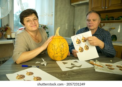 Making Jack O'Lantern at home. The process of creating a Jack O'Lantern theme template. A man and a woman are preparing a pumpkin for carving.