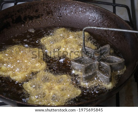 making kokis or rosette cookies, crispy sri lankan food made out of rice flour and coconut milk, closeup view of frying kokis in a pan with a flower shape mold, preparing traditional dish