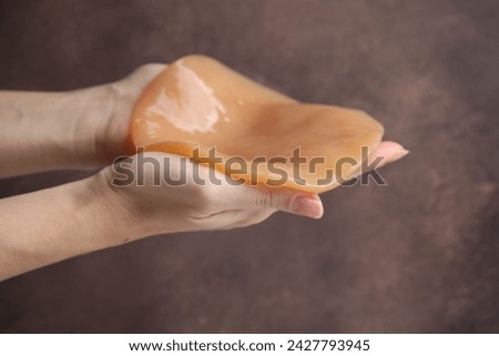 Making kombucha. Woman holding Scoby fungus on brown background, closeup