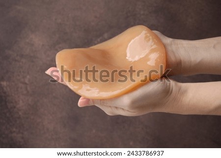 Making kombucha. Woman holding Scoby fungus on brown background, closeup