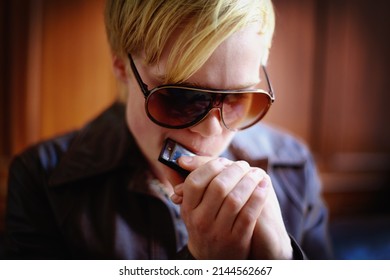 Making mellow music. Attractive young guy in urban wear playing the harmonica. - Powered by Shutterstock