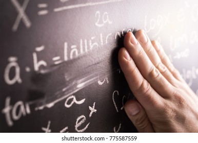 Making mistakes and wrong answer concept. Hand wiping math formula off blackboard in classroom at school. Student or teacher correcting incorrect calculation on chalkboard. - Powered by Shutterstock