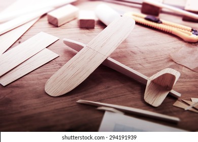 Making model airplane from wood. Wooden air plane handcrafted with balsa wood, on work table. tools and Materials on table. Intentionally shot in retro-impression color, and shallow depth of field.