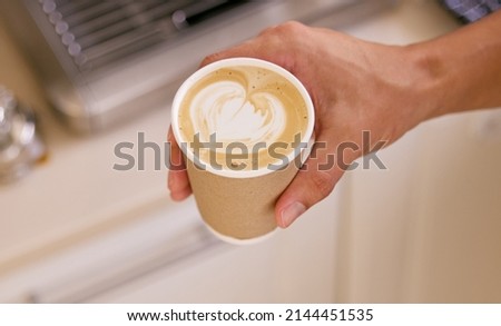 Making my coffee extra special for myself. Shot of an unrecognizable man holding a cup of coffee with coffee art.