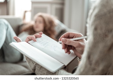 Making notes. Close up of professional psychologist making notes listening to stressed client