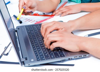 Making notes. Cropped image of two creative people in smart casual wear typing something on laptop while having a brain storming in the meeting room