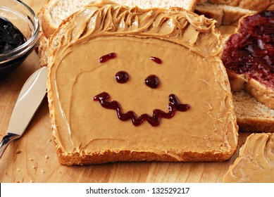 Making peanut butter sandwiches with personality!  Fun smiley face drawn on with jam. Creamy peanut butter with jam on whole grain wheat bread on wood cutting board. Macro with shallow dof. - Powered by Shutterstock