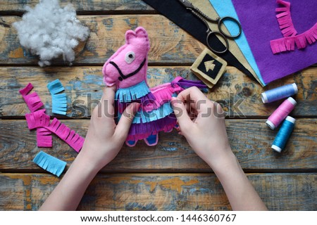Making pink lama. Sewing toys from felt with your own hands. DIY concept for children. Handmade crafts. Step 5. Decorate the toy.