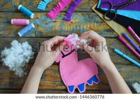 Making pink lama. Sewing toys from felt with your own hands. DIY concept for children. Handmade crafts. Step 4. Stuff the toy with padding polyester.