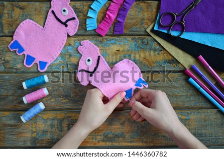 Making pink lama. Sewing toys from felt with your own hands. DIY concept for children. Handmade crafts. Step 3. Sew all details of toy.