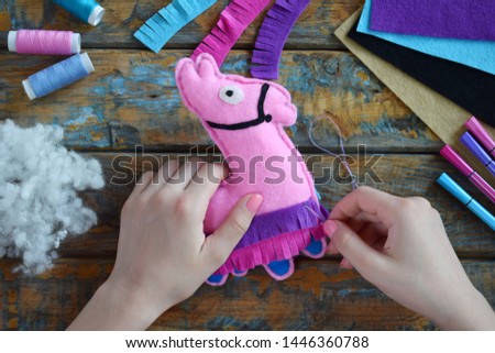 Making pink lama. Sewing toys from felt with your own hands. DIY concept for children. Handmade crafts. Step 3. Sew all details of toy.