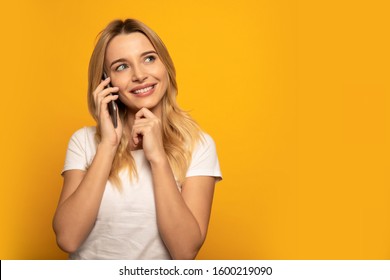 Making plans. Close-up photo of an elegant woman, who is looking to the right-upper corner and holding her chin with her left hand, while talking on the phone.