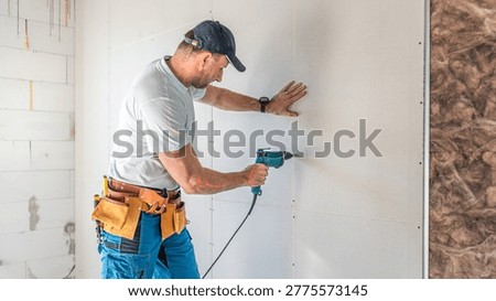 Making a plasterboard partition. A drywaller using an electric quick screwdriver for plasterboard fixing.