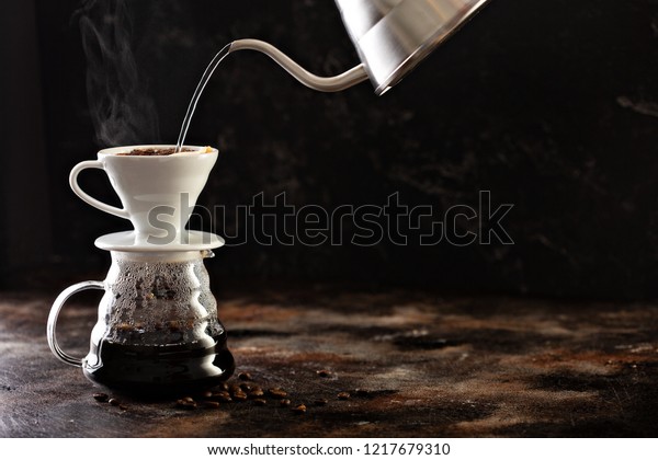 Making pour over coffee with hot water being\
poured from a kettle