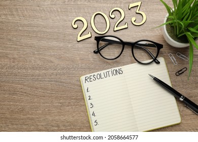 Making Resolutions For 2023 New Year. Flat Lay Composition With Notebook On Wooden Table