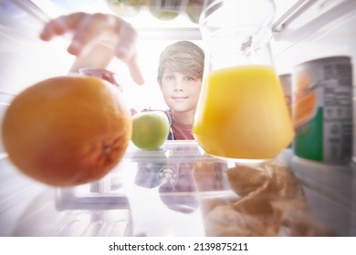 Making The Right Choice.... Shot Of A Young Boy Reaching Into The Fridge For A Snack.