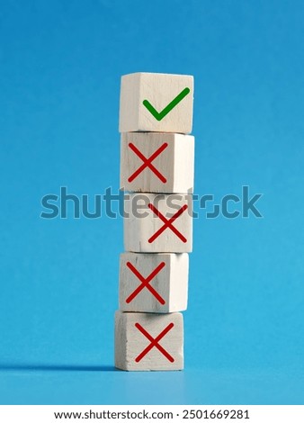 Making the right decision after wrong ones. Stack of wooden cubes is showing one right choice against many wrong ones over a blue background.