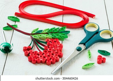 Making rowan in quilling technique. Scissors, paper strips and detail design on a white wooden table. Selective focus