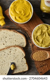 The making of a sandwich with two different mustards in ramekins, Rye bread and mustard seeds and bottles of mustard.