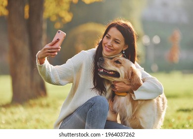 Making selfie. Young woman have a walk with Golden Retriever in the park. - Powered by Shutterstock