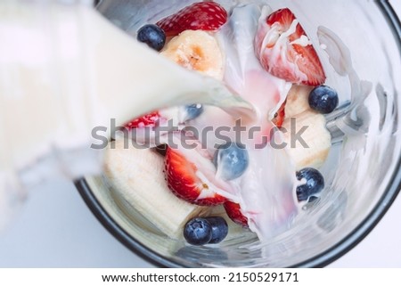 Making smoothie or milkshake in blender. Pouring milk in a blender with fruits. Vegan smoothie with almond milk Foto d'archivio © 