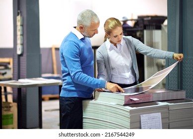 Making sure every little nuance is perfect. Two publishers assessing the quality of printed work in a factory.