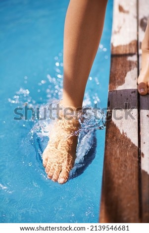 Making sure that I dont become an ice-cube. Shot of a woman testing the temperature of the pools water using her foot.