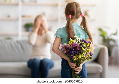 Making Surprise. Rear view of girl hiding flowers for mum or granny behind back, greeting woman with mother's day or birthday, spending time together at home, lady covering eyes, selective focus