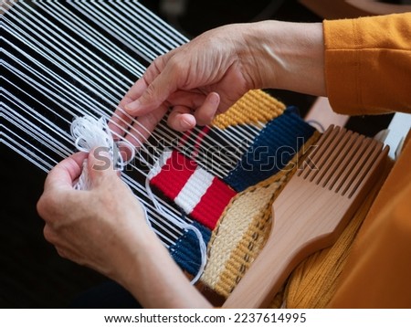 Making a tapestry with an image of lighthouse, selective focus. Creating handmade wall decoration using weaving loom, beater and threads. Hobby concept