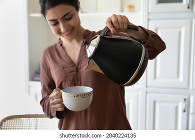 Making tea. Happy young woman of indian ethnicity hold cup teapot in hands brew instant coffee black green herbal tea to drink with pleasure. Millennial hindu female prepare hot drink in ceramic mug - Powered by Shutterstock