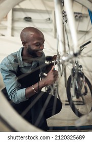 Making this bike feel brand new. Shot of a handsome young man crouching alone in his shop and repairing a bicycle wheel.