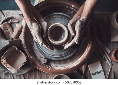 Making it together. Top view of potter teaching child to make ceramic pot on the pottery wheel - Shutterstock ID 507378352