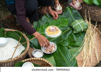 Making (wrapping) Chung Cake, the Vietnamese lunar new year Tet food outdoor with old woman hands and ingredients. Closed-up.
