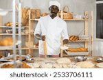 Making yeast dough in bakery - male baker rolling out dough with a rolling pin